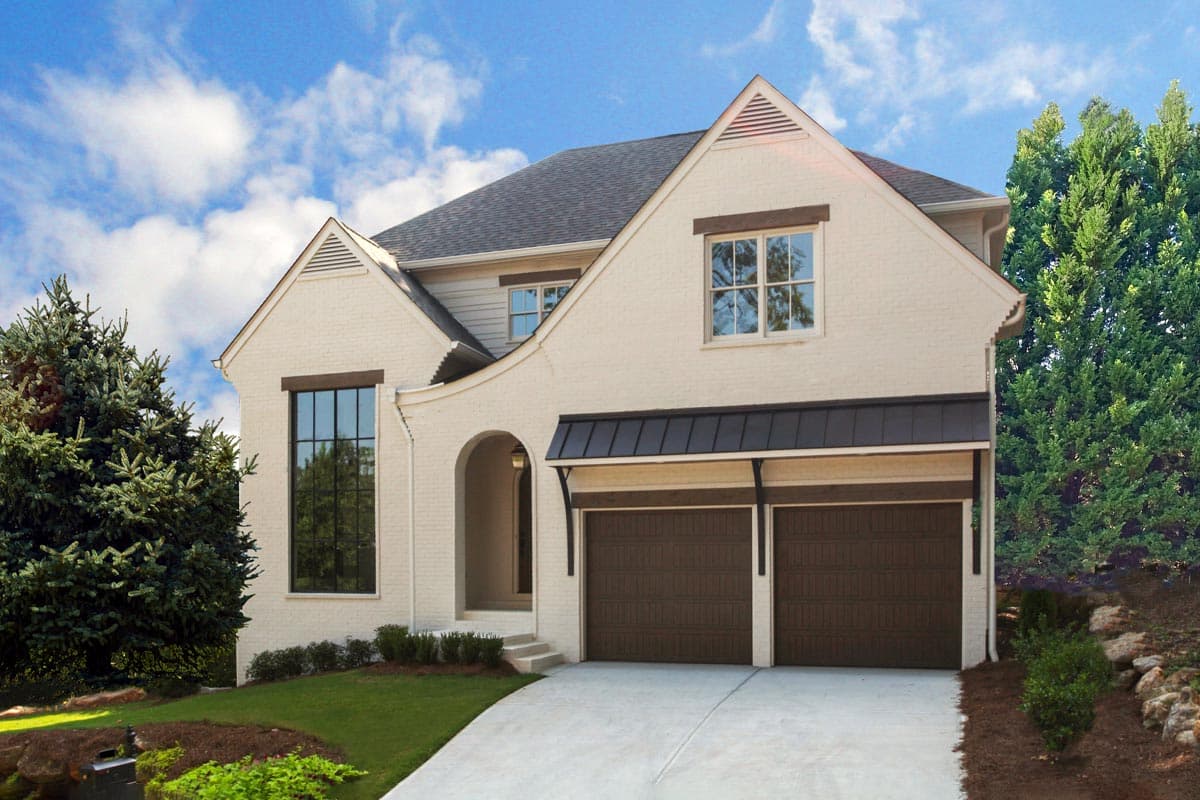 House plan exterior. Two-story with brick facade. Features include gabled roof, arched entry, dormers, and two-car garage with a metal awning.