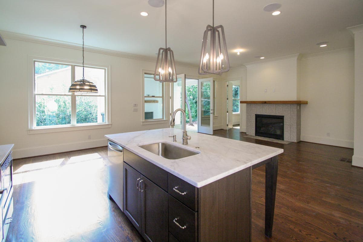 Open concept living area with kitchen island, marble countertops, fireplace, and large windows.