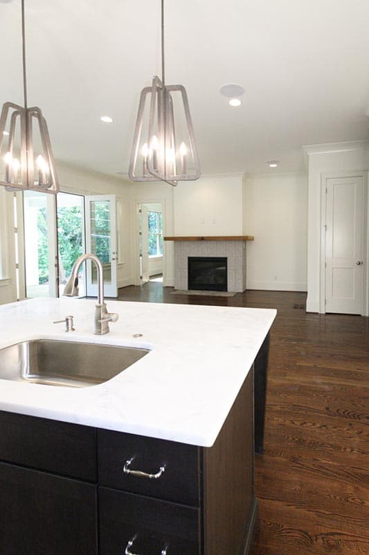 Interior view of a house plan: island with sink, fireplace, and French doors leading to an outdoor area.