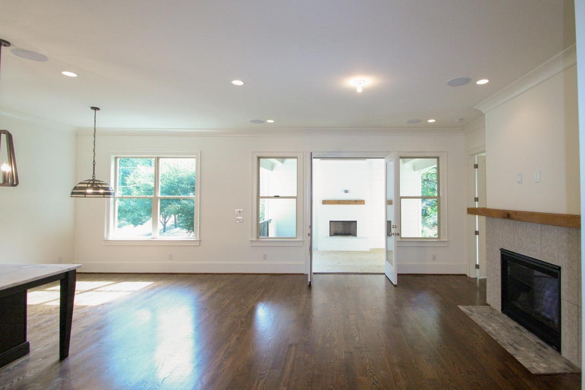 Open concept living area with hardwood floors, fireplace, large windows, and double doors to another room with a fireplace.
