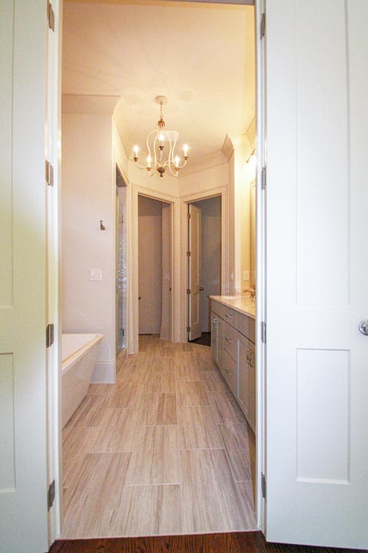 Bathroom interior with bathtub, vanity, shower stall, and chandelier with multiple doorways.