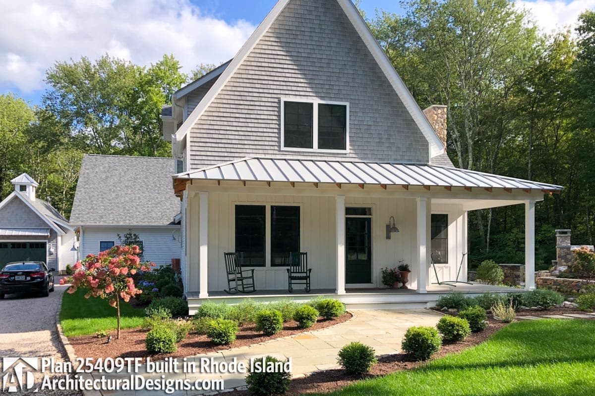 House plan exterior: Two-story home with a metal-roofed porch, shingle siding, dormers, and stone chimney.