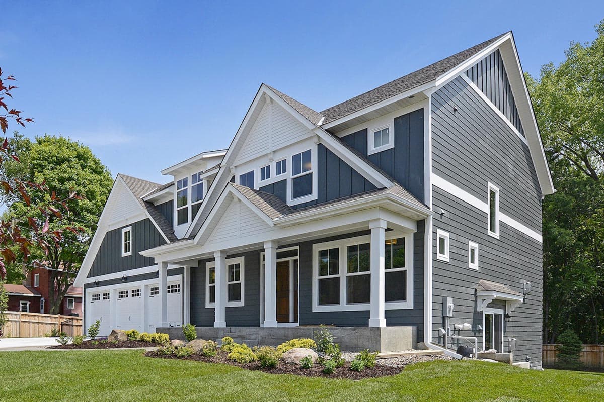 House plan exterior: Two-story Modern Farmhouse with a covered front porch, three-car garage, dormers, and gabled rooflines.