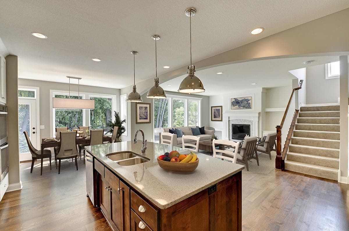 Open-concept living space with island kitchen, dining area, fireplace, and staircase.