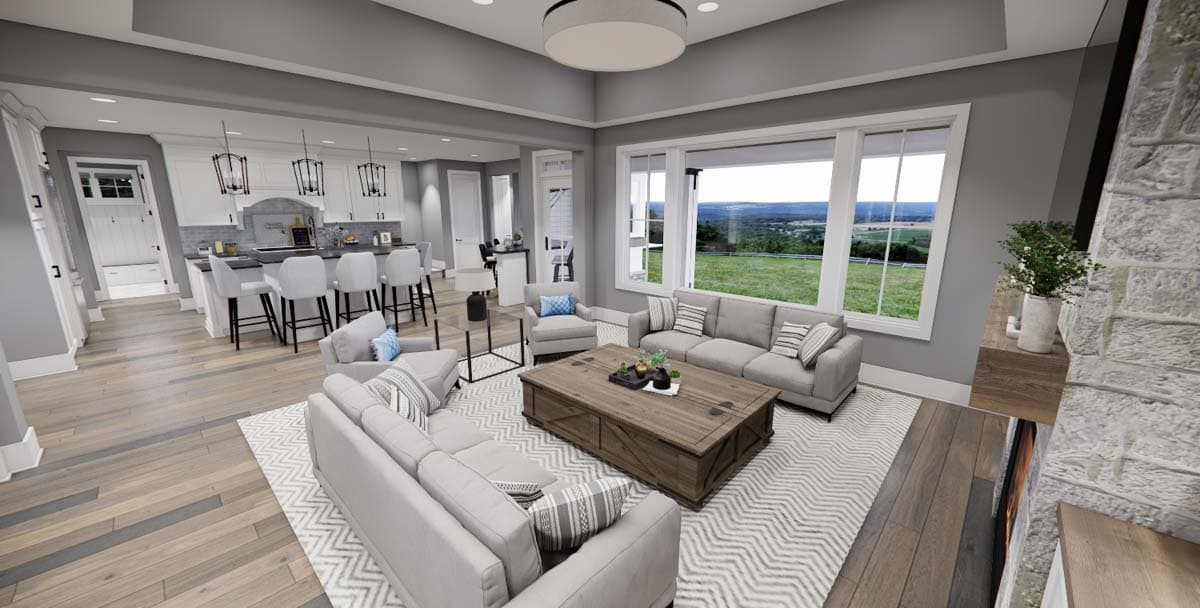 Open-concept living area and kitchen with large windows, island seating, and neutral-toned furniture.