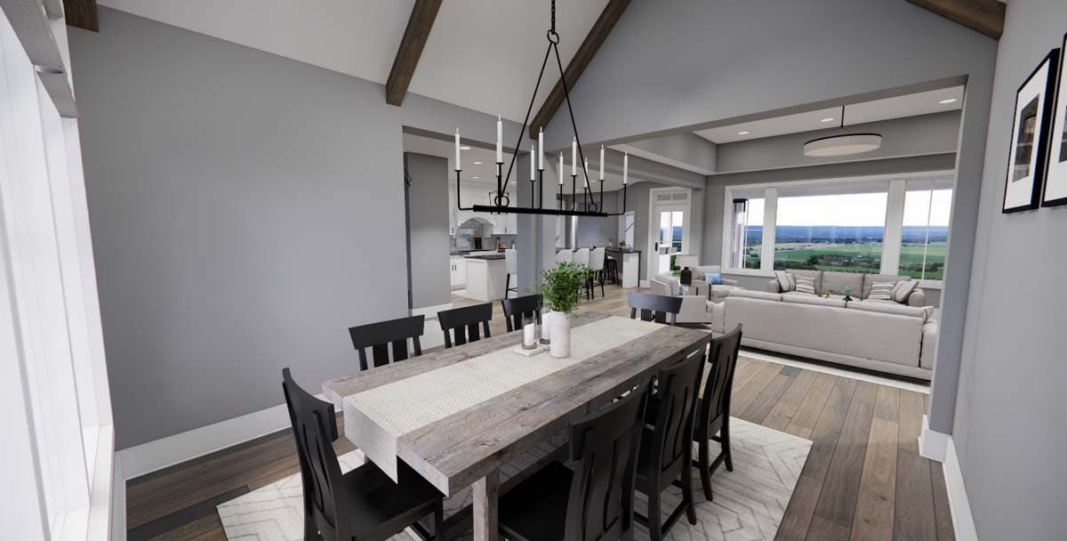 Dining area with vaulted ceiling and exposed beams, open to kitchen and living room with large windows.
