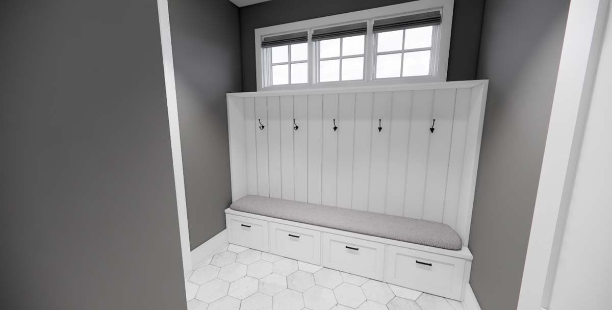 Mudroom built-in with paneled back, storage drawers, padded seat, and coat hooks below a tripartite window.