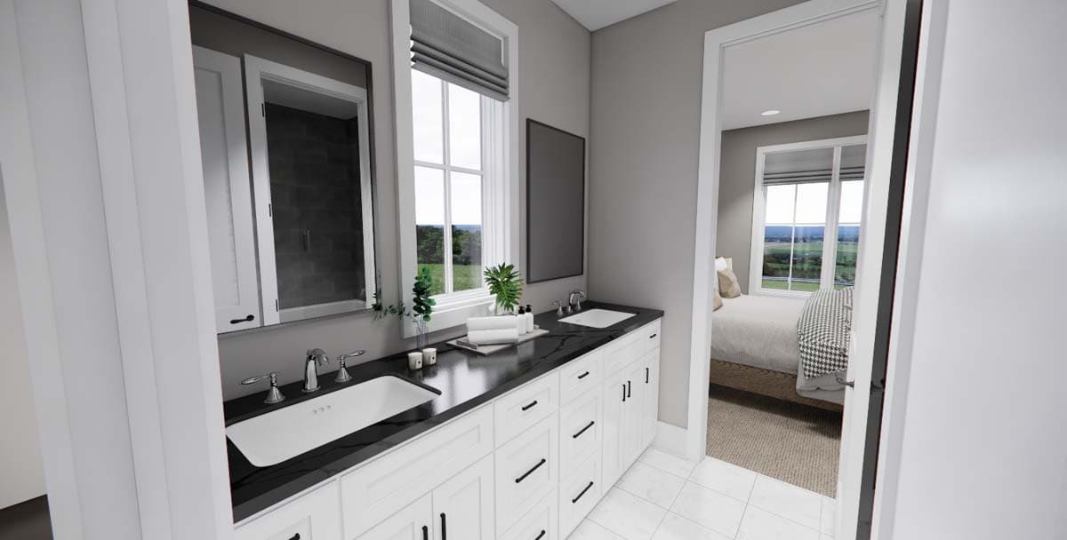Modern bathroom with double vanity, white cabinetry, and black countertop; view of bedroom beyond.