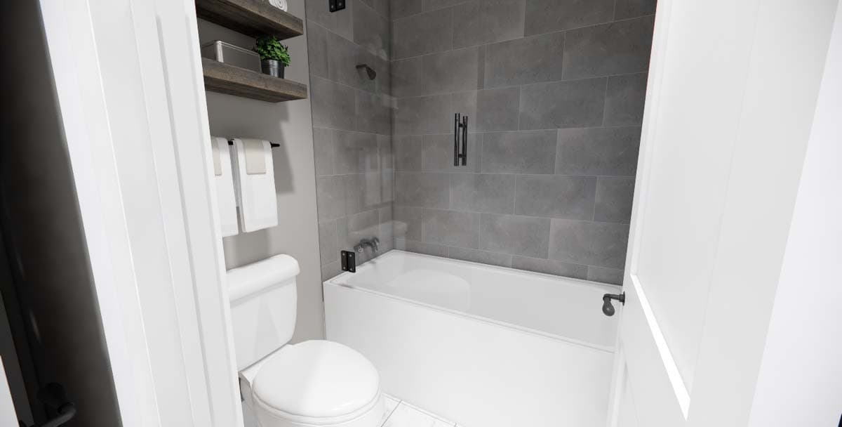 Bathroom interior featuring a bathtub with gray tiled walls, toilet, and wooden shelves with towels.