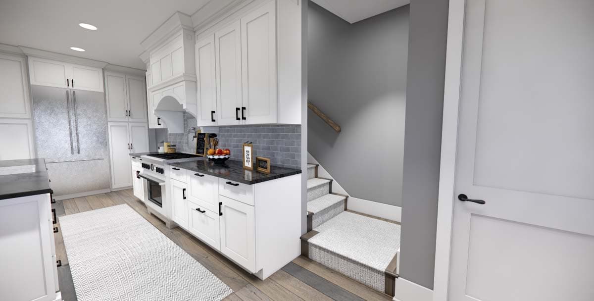 Kitchen with white cabinets, stainless steel refrigerator, gas range, and carpeted stairs leading up.