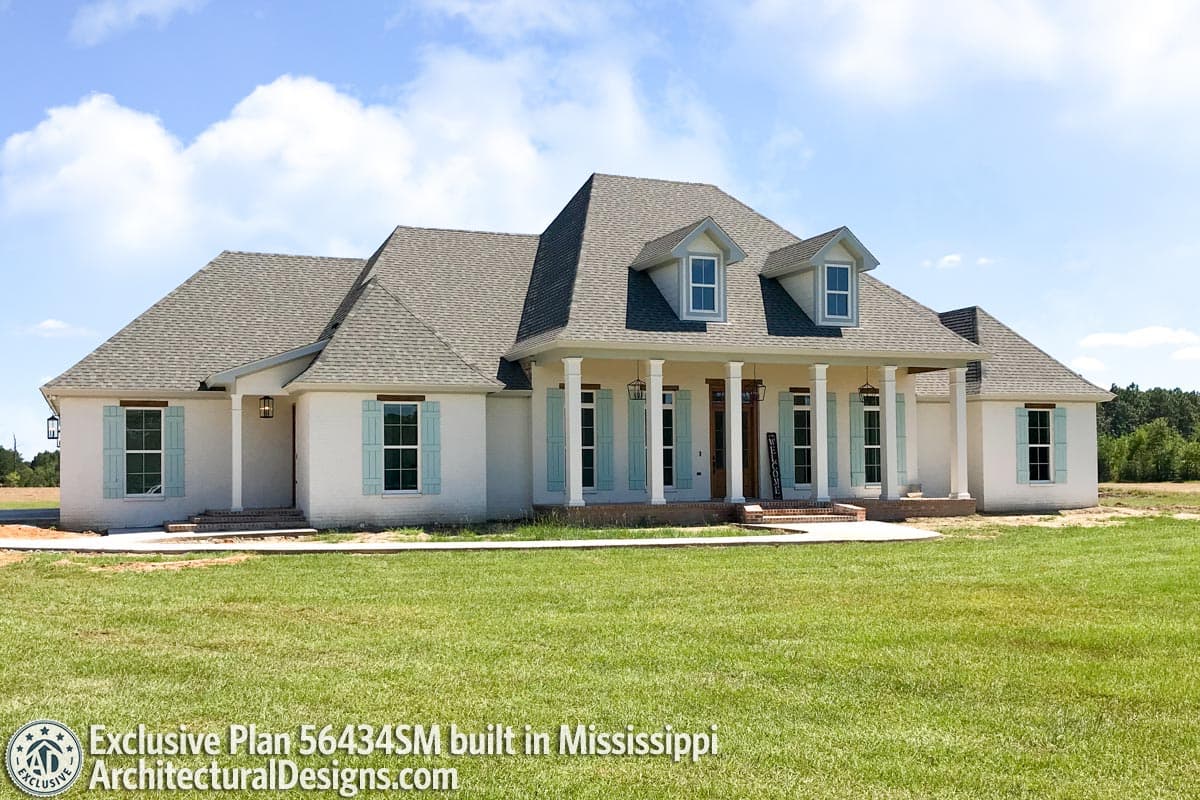 House plan exterior featuring a wide covered porch with columns, dormers, and light blue shutters.