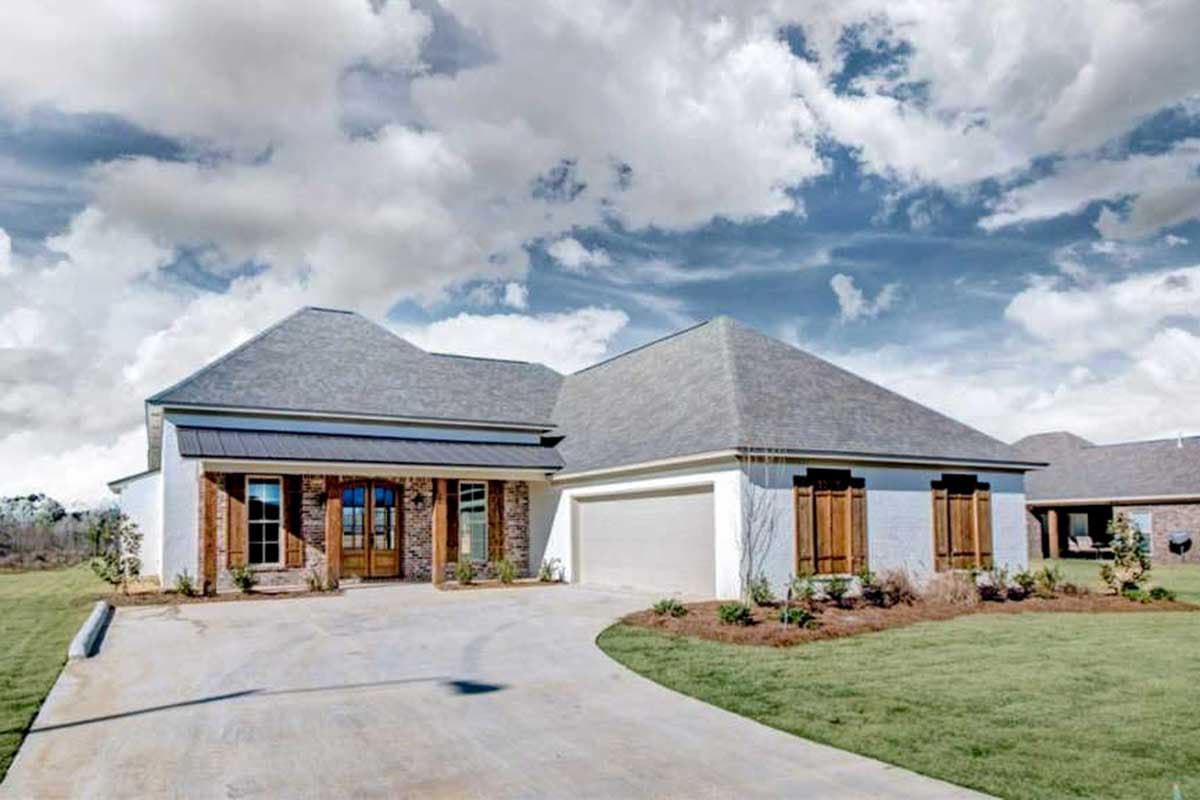 House plan exterior: single-story, white brick, covered entry with timber posts, gable roof, and attached garage.