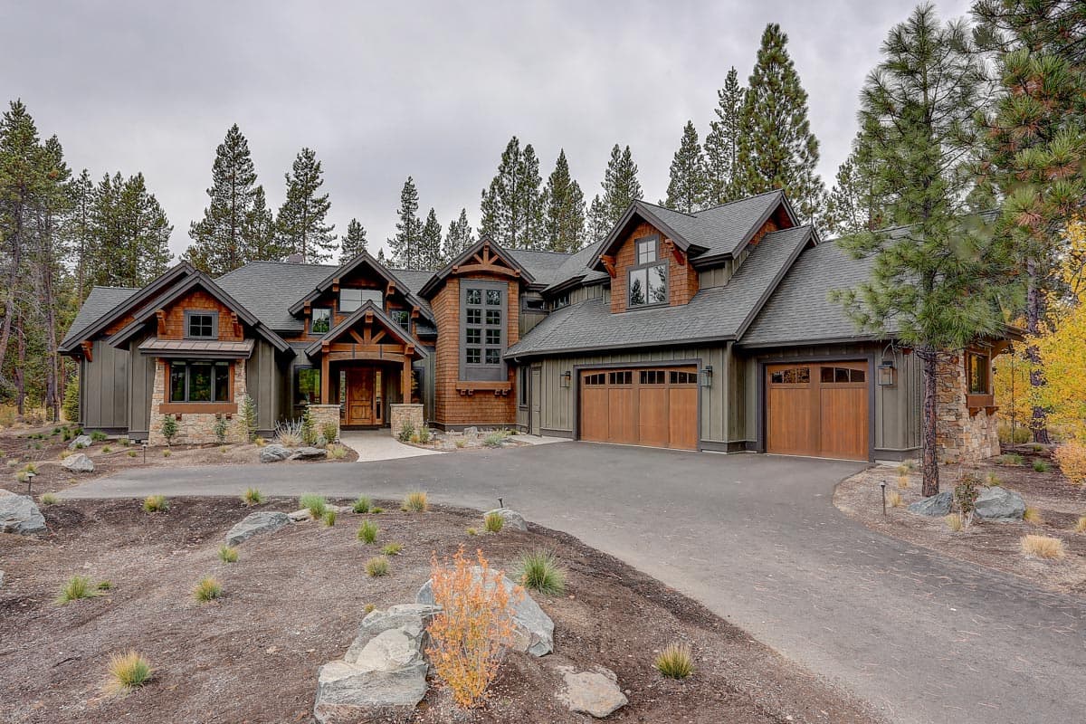 Modern Craftsman style house plan exterior with multiple gables, a prominent timber-framed entrance, and a three-car garage.