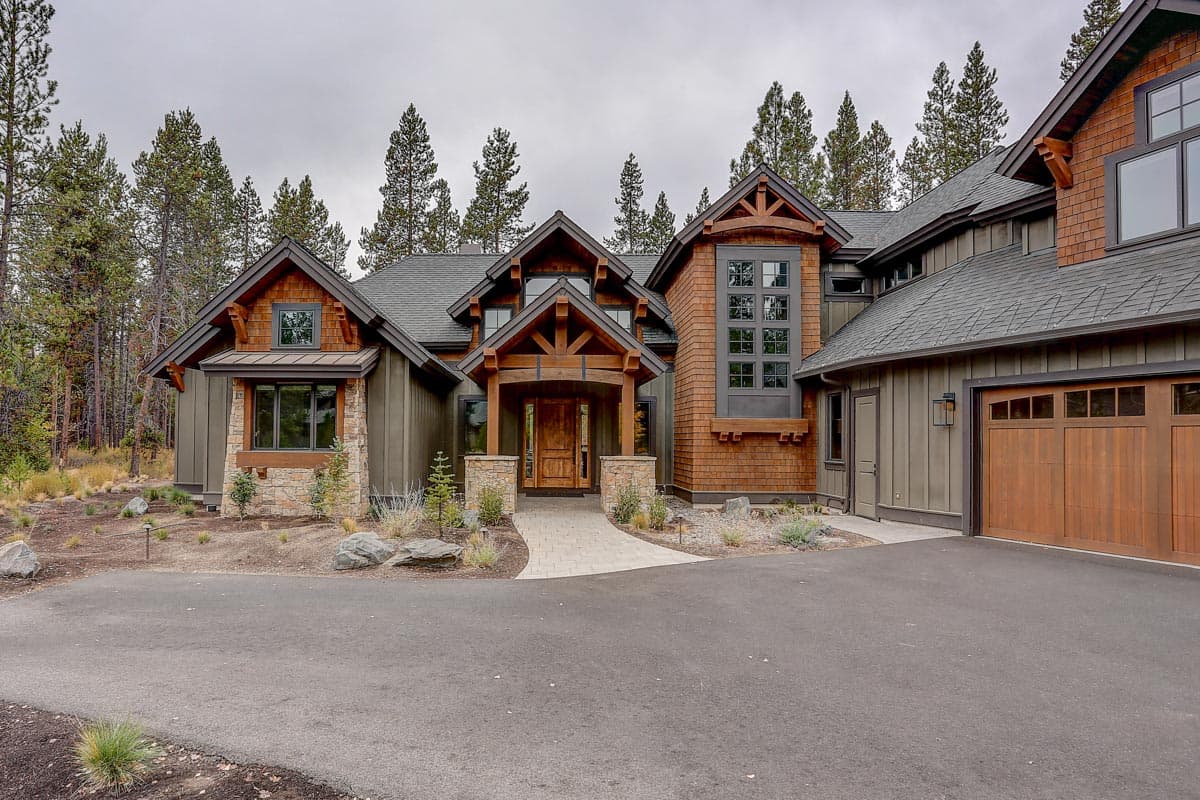 House plan exterior: Rustic lodge style, two stories, timber-framed covered entryway, stone accents, and wood garage door.