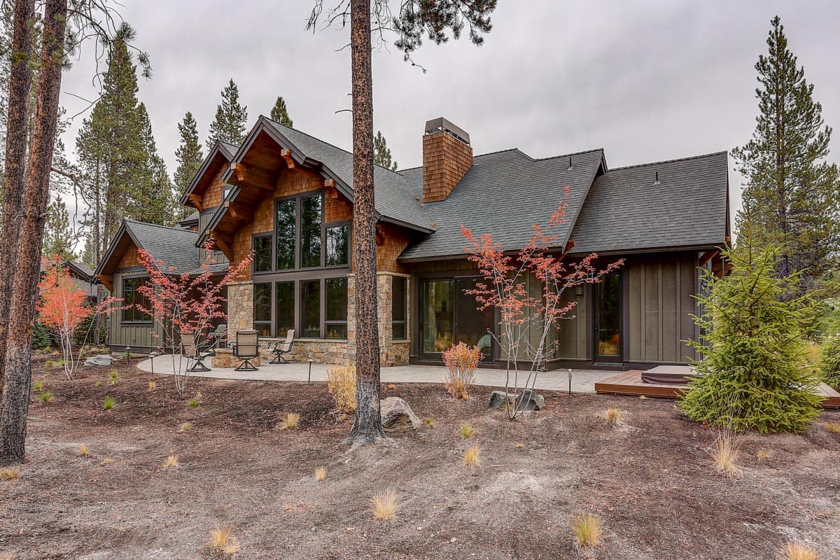House plan exterior with stone and wood siding, large windows, gabled rooflines, and covered patio.