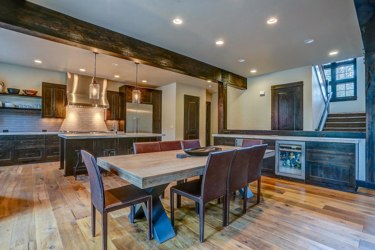 Open-concept living space featuring a kitchen with island, dining area with table, and a wine cooler next to stairs.