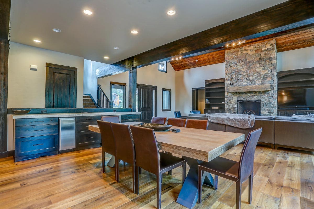 Open concept living area with dining table, stone fireplace, built-in shelving, and bar area.