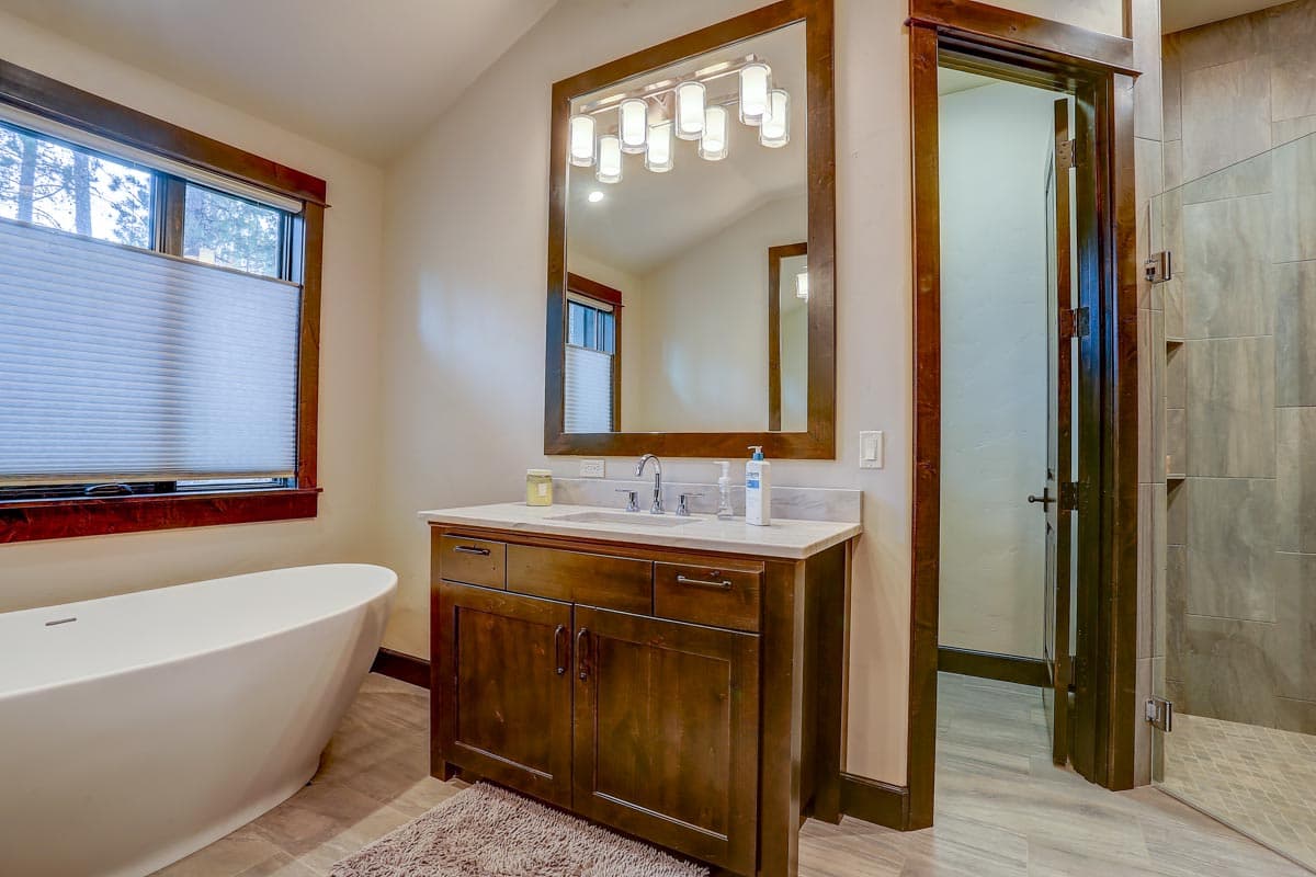 Bathroom with freestanding tub, wooden vanity with dual sinks, large mirror, and tiled walk-in shower.