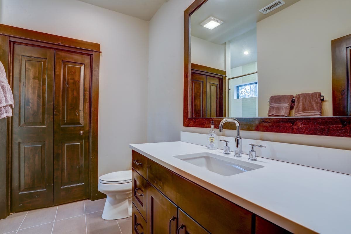 Bathroom with wood grain double doors, white vanity with integrated sink, chrome faucet, and toilet.