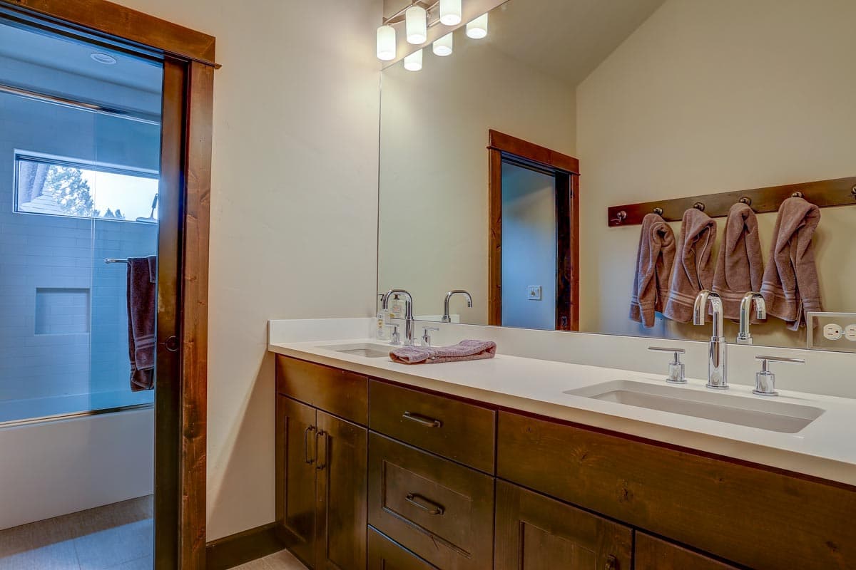 Bathroom with double vanity, white quartz countertop, dark wood cabinets, and glass-enclosed shower visible to the left.