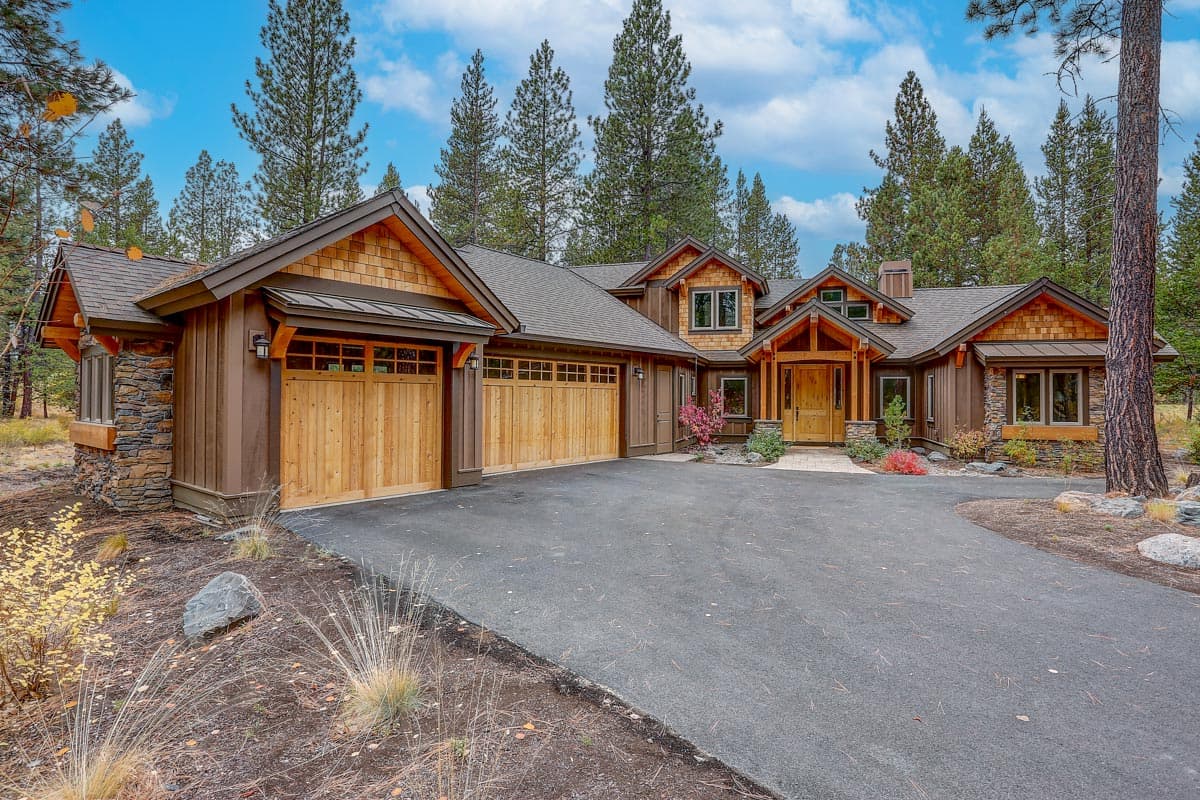 House plan exterior. Craftsman style, two-story home with gables, wood shake siding, and attached garage. Stone accents and covered entry porch.