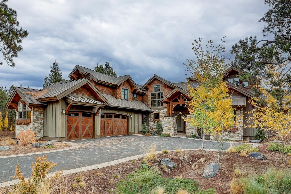 House plan exterior with Craftsman style, multiple gables, and wood-paneled garage doors. Features stone accents, covered entry, and mixed rooflines.