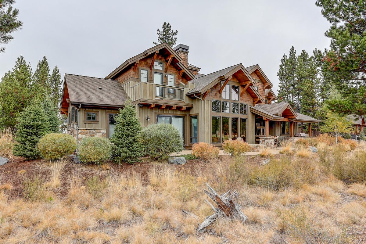 Mountain style house plan exterior with multiple gables, large windows, stone accents, and a covered porch.