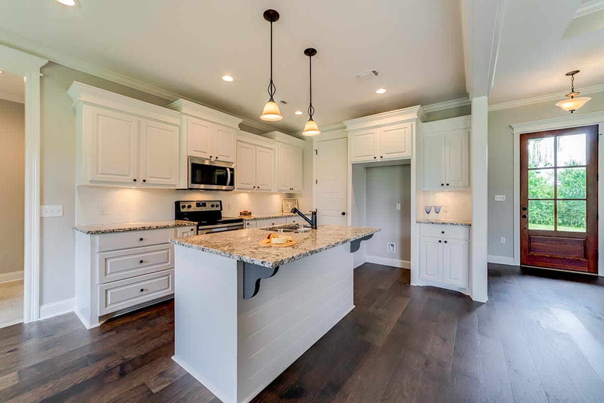 Kitchen featuring white shaker cabinets, granite countertops, stainless steel appliances, and a center island with pendant lighting.