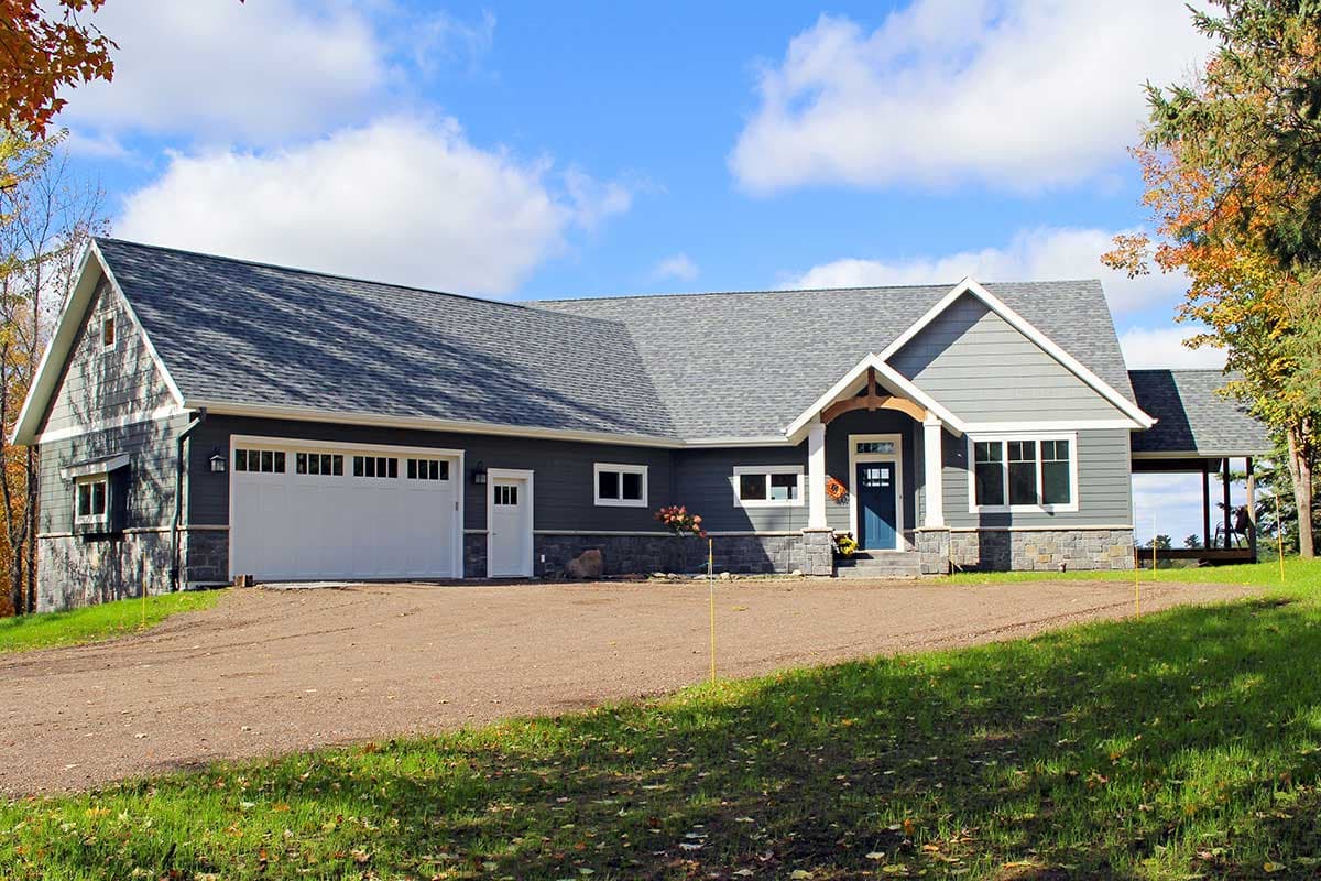 House plan exterior. Craftsman style, single story home with gabled roof, stone facade, and attached garage. Includes a covered porch.