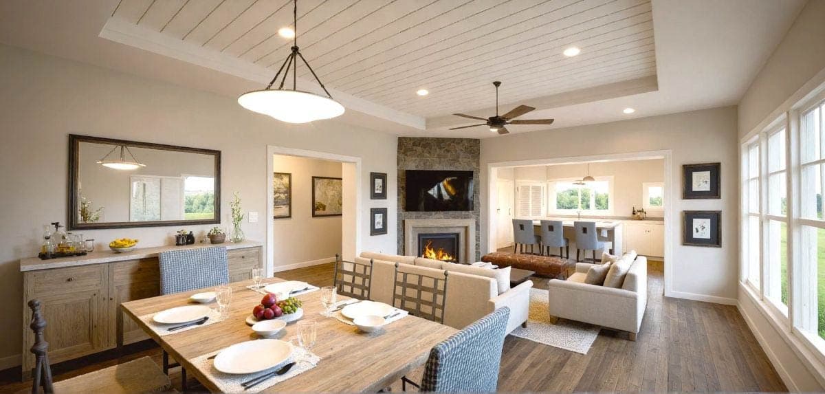 Open concept great room with fireplace, dining area, and kitchen with island seating. Coffered ceiling detail.