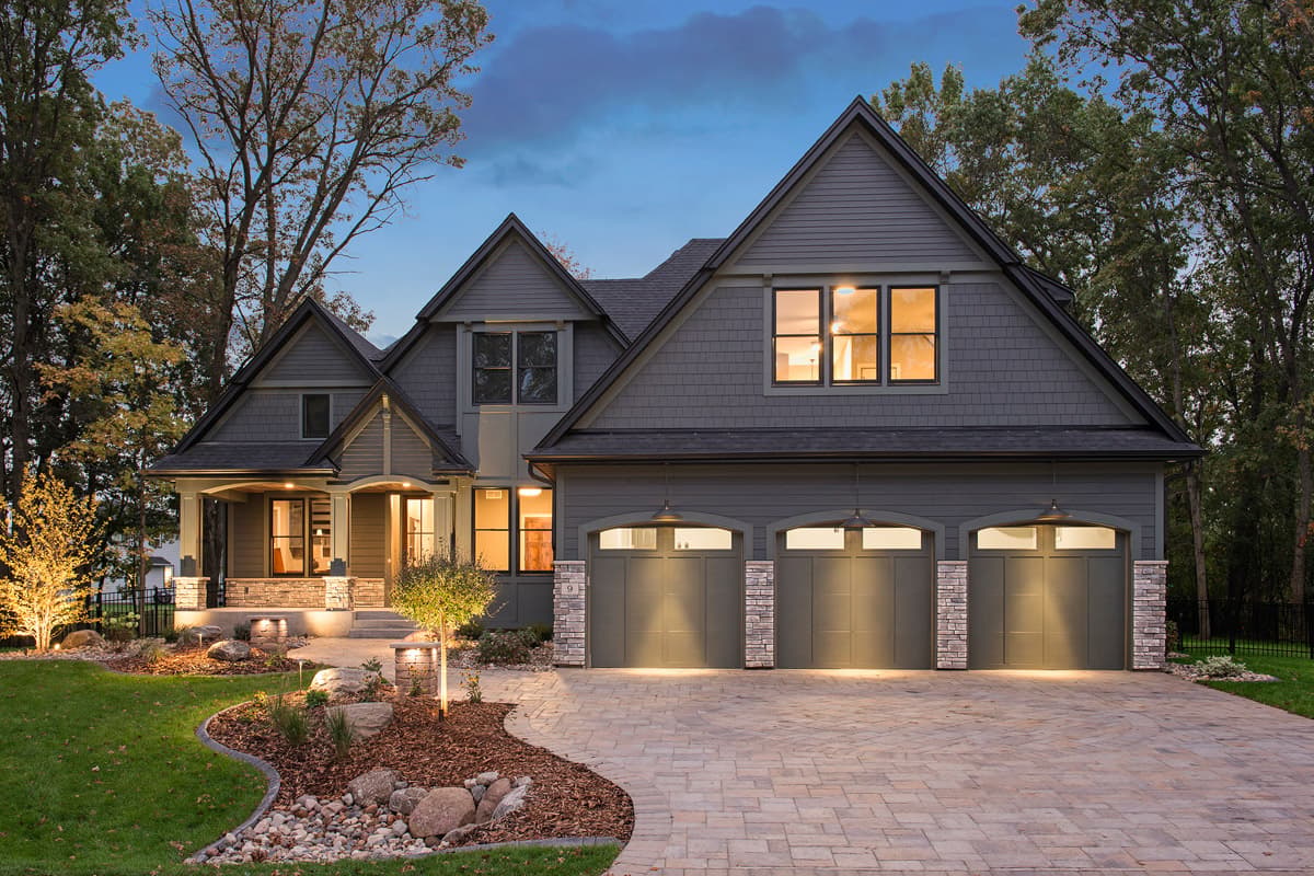 Modern Farmhouse house plan exterior with a covered front porch, gables, and a three-car garage with stone accents.