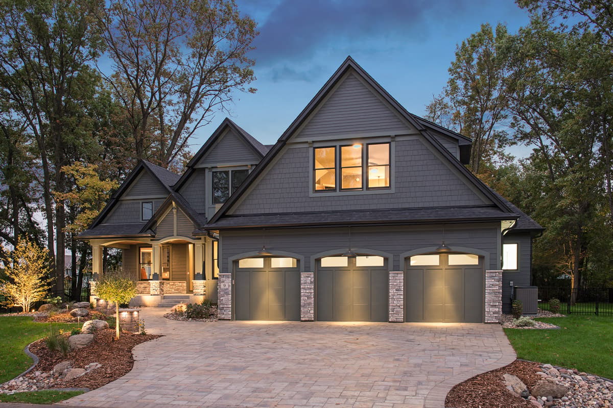Modern Farmhouse house plan exterior with three garage bays, prominent gables, covered entry porch, and stone accents.