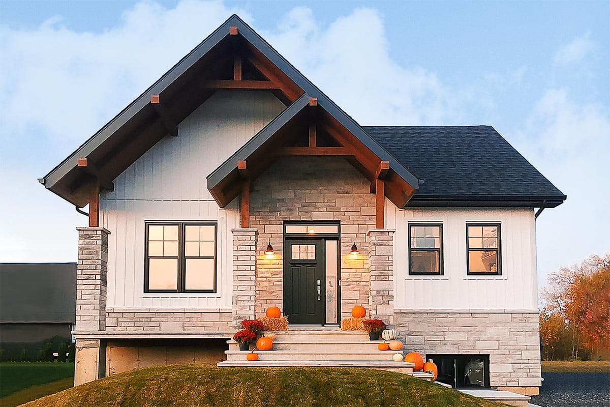 House plan exterior with board and batten siding, gable roof, and stone-clad foundation. Features include a covered entry and exposed timber brackets.
