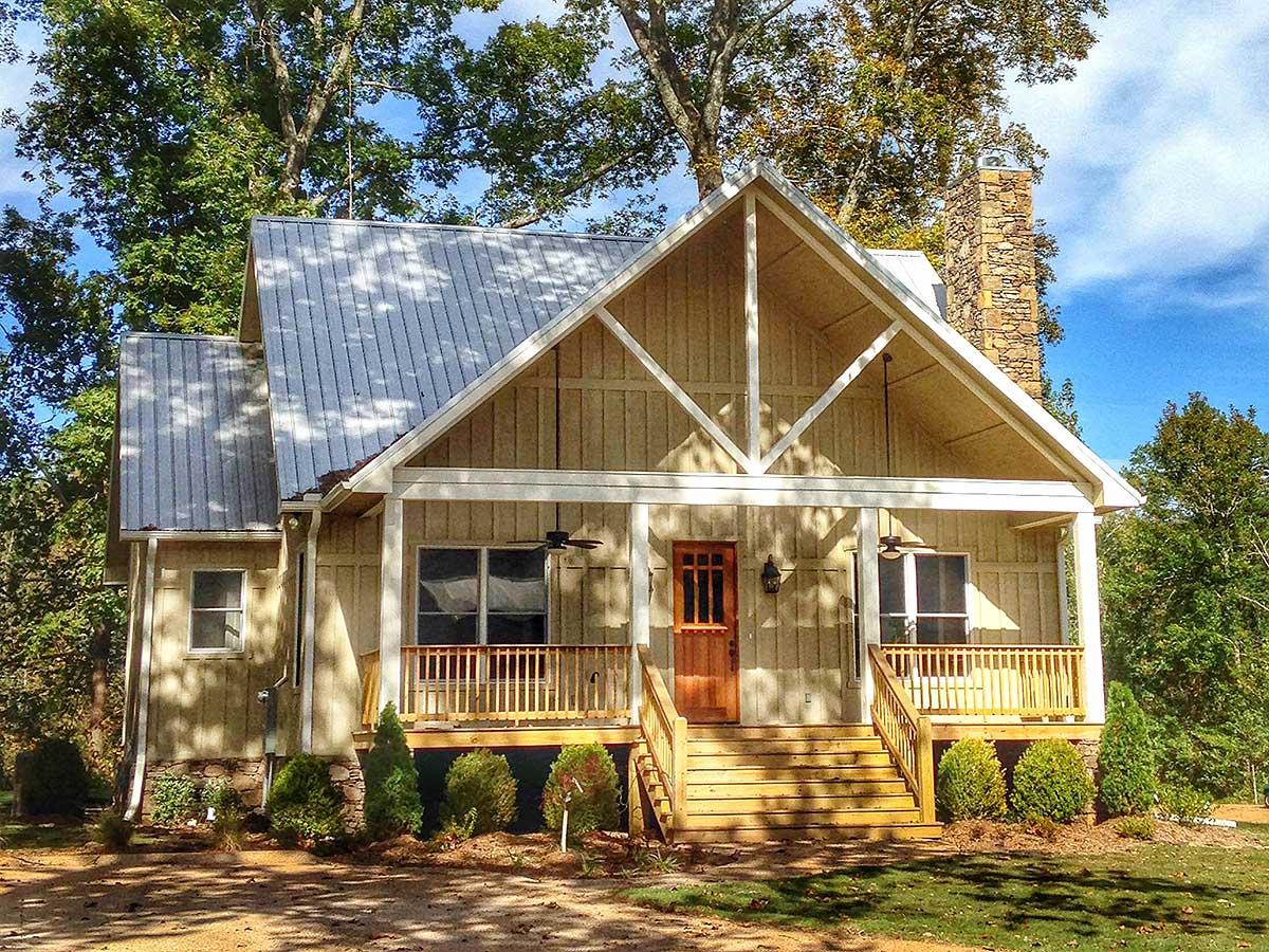 House plan exterior with two stories, a gabled roof, a porch, and a stone chimney. Features wooden trim and a metal roof.