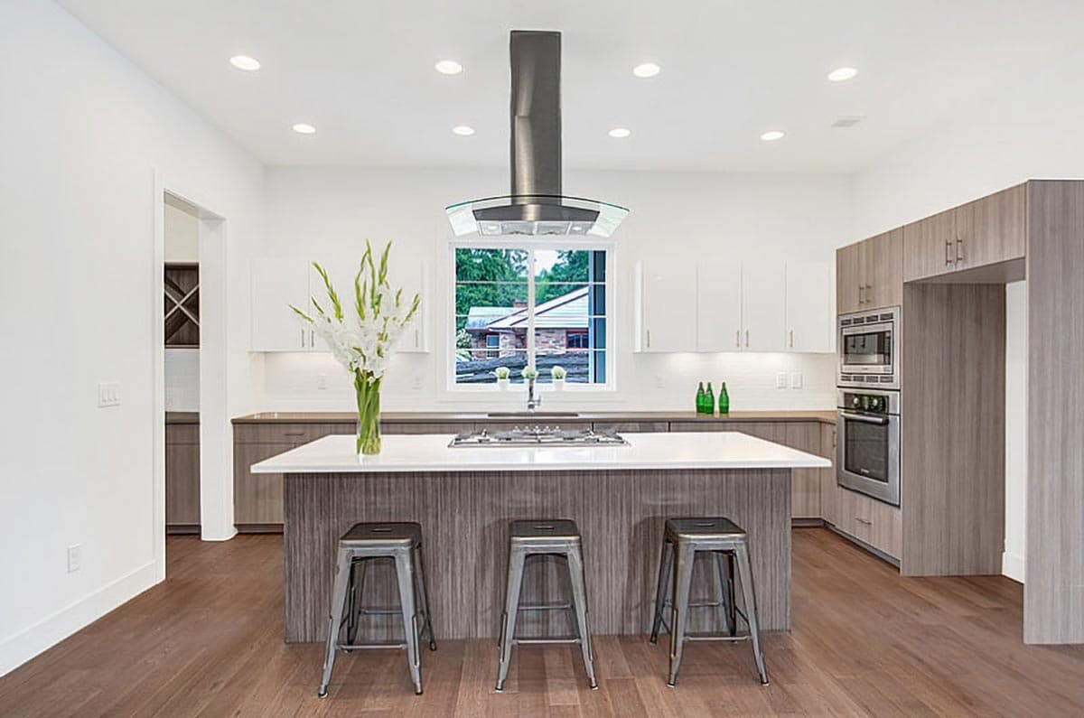 Modern kitchen with island, stainless steel appliances, gas range, and large window overlooking the outdoors.