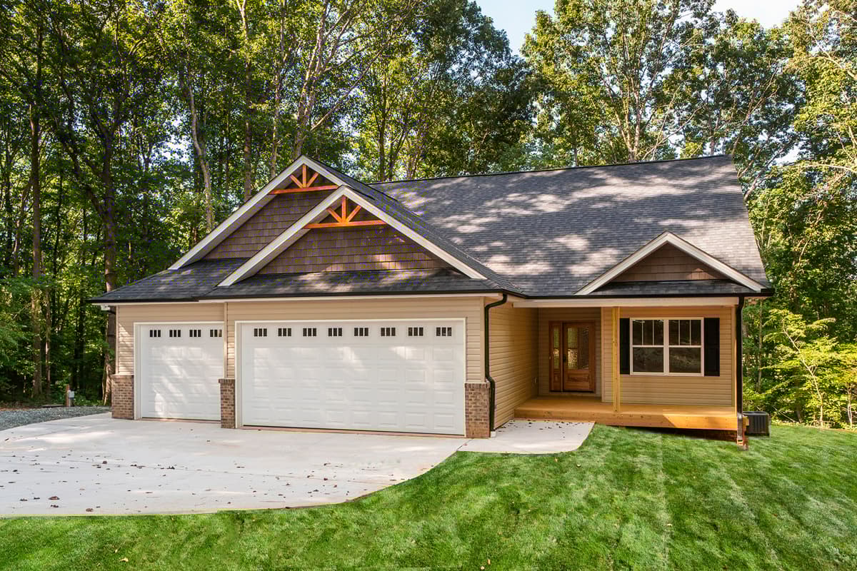 House plan exterior with two-car garage, front porch, and gable roof. Exterior features wood shake siding and decorative gable accents.
