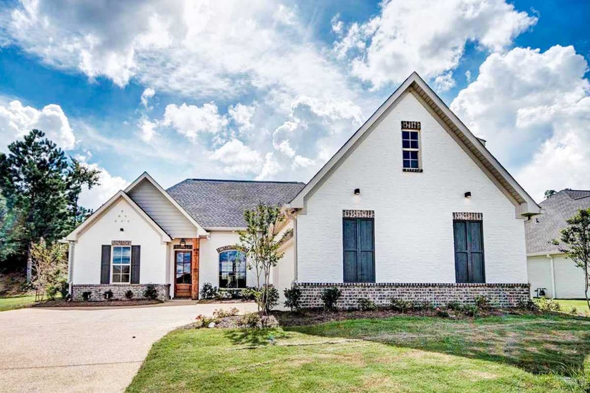 House plan exterior with white brick, gables, dormers, dark shutters, and a covered entry.