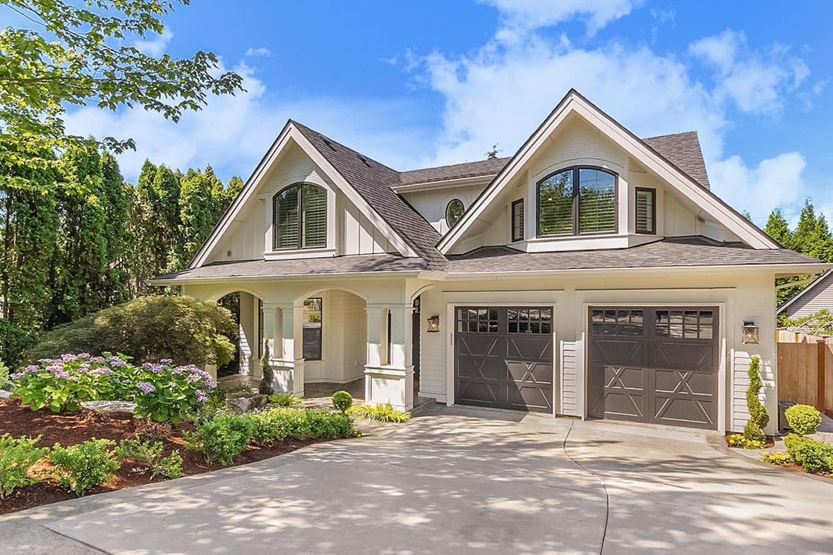 House plan exterior. Two-story Modern Farmhouse with gabled roof, arched windows, and covered porch. Two-car garage with paneled doors.