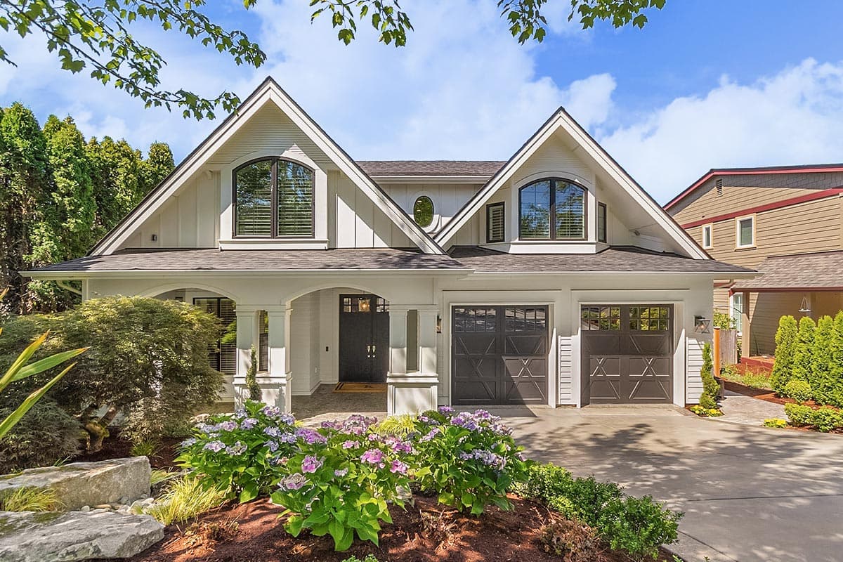 House plan exterior featuring a Modern Farmhouse style, two stories, dual gables, arched dormers, covered entryway, and a side-facing triple garage.