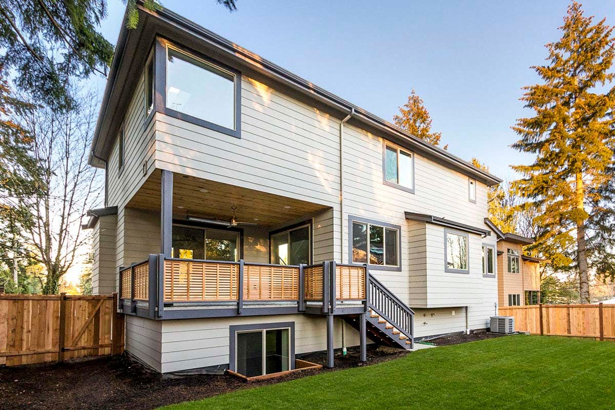 Modern two-story house plan exterior with a covered deck, large windows, and slatted wood railings.