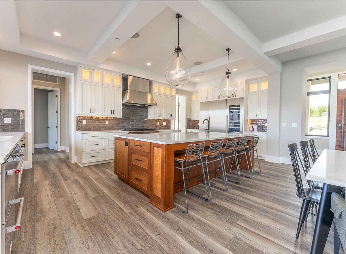Modern kitchen with large island, white cabinetry, stainless steel appliances, and pendant lighting.