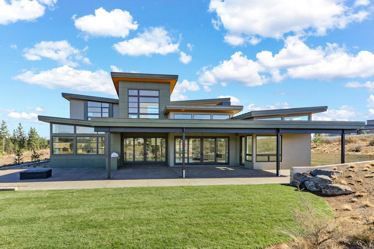 Modern house plan exterior with a cantilevered roof, extensive glazing, and an expansive covered patio.