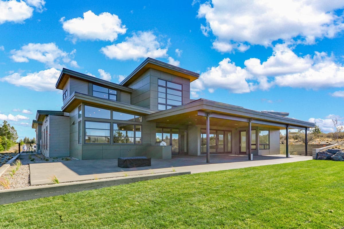 Modern house plan exterior with multiple gables, large glass windows, and a covered patio.