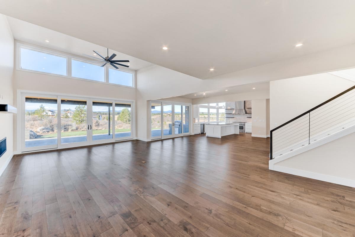 Open concept great room and kitchen with vaulted ceilings, large windows, sliding glass doors, and island.