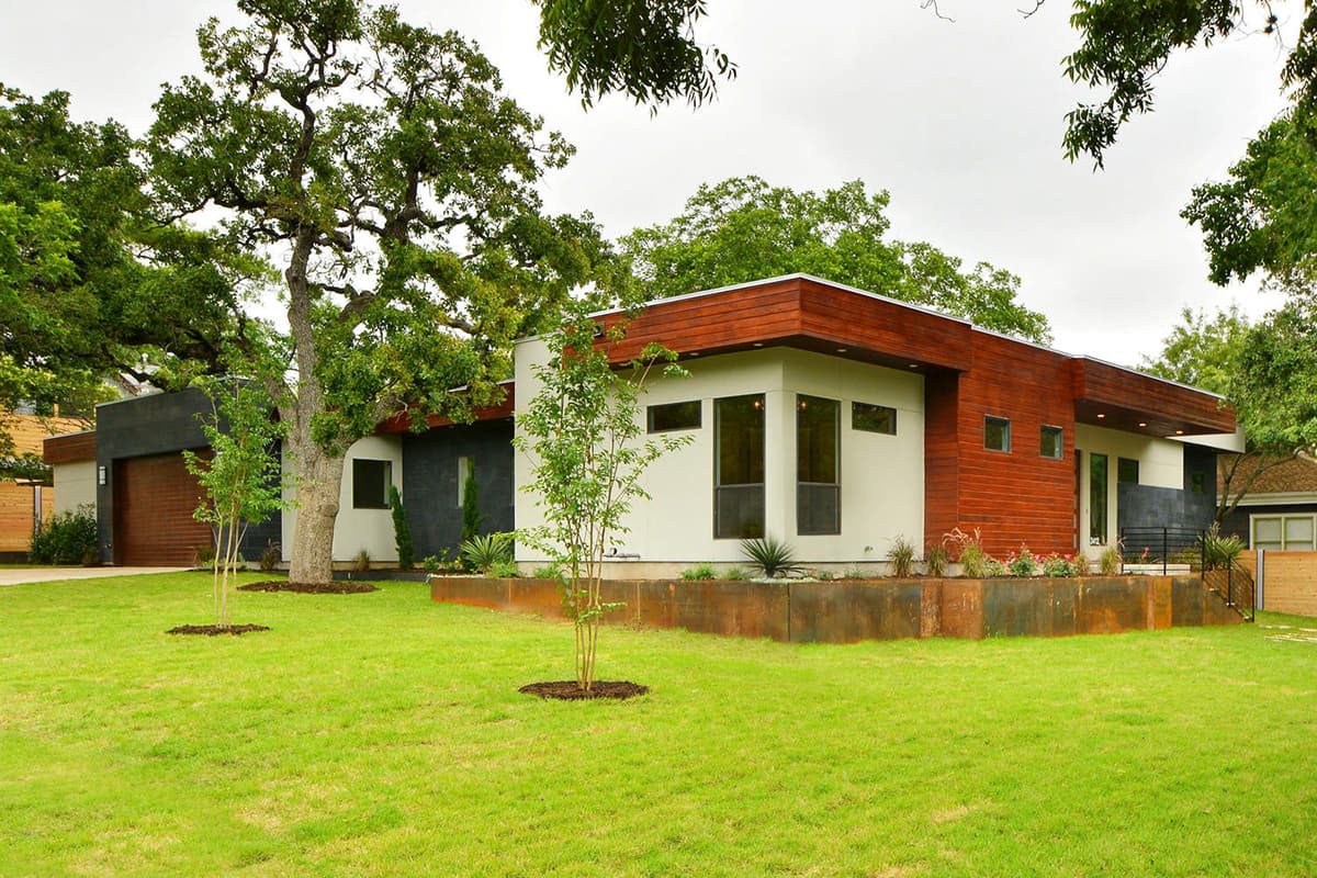 Modern house plan exterior with wood siding, white stucco, dark stone accents, and a detached garage with wood doors.
