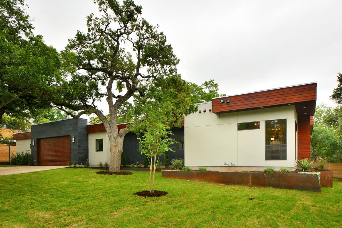 Modern single-story house plan exterior with flat roof, wood accents, garage, and dark stone facade.