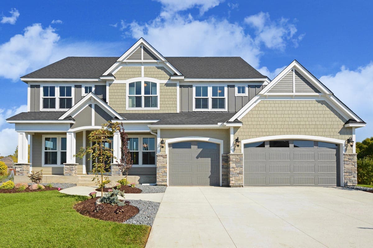 Two-story house plan exterior with a mix of shingle and board-and-batten siding, arched garage doors, and multiple gables.