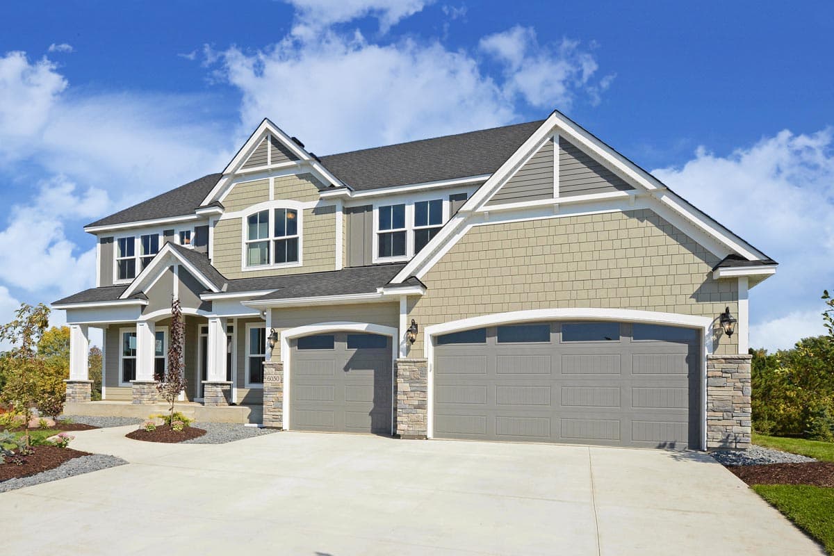 House plan exterior: Two-story home with gabled dormers, shingle siding, stone accents, and a three-car garage.