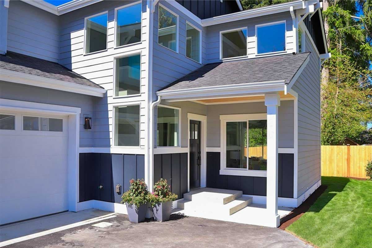 Modern two-story house plan exterior with multi-pane windows, covered porch, and attached garage.