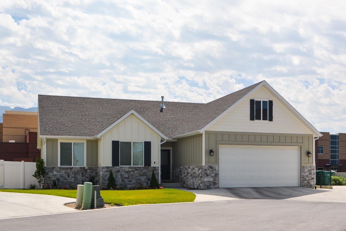 Modern Farmhouse house plan exterior with two stories, gable roof, white garage door, and stone accents.